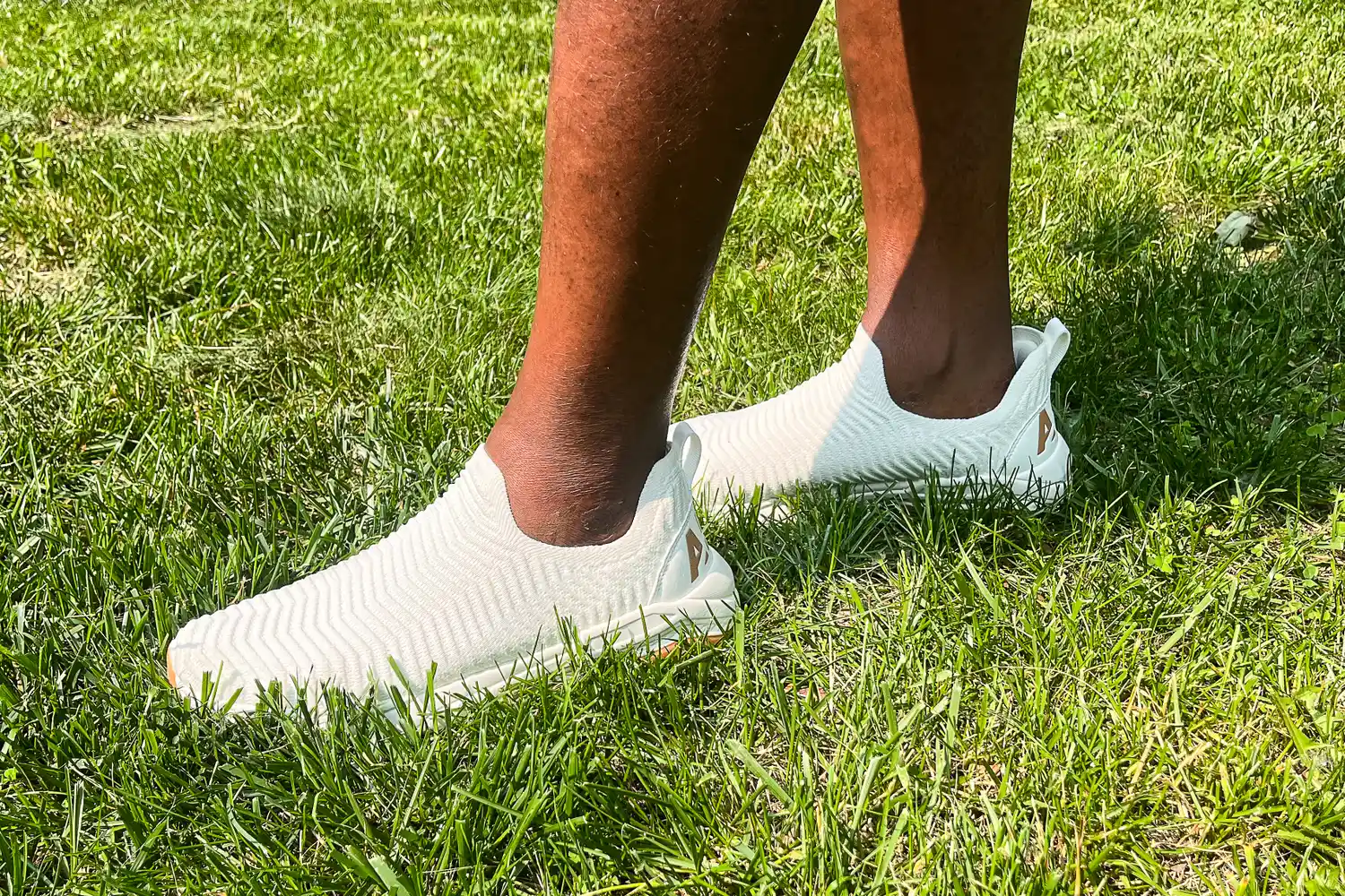 A person walks through grass while wearing the APL Men's TechLoom Travelers