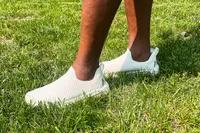 A person walks through grass while wearing the APL Men's TechLoom Travelers
