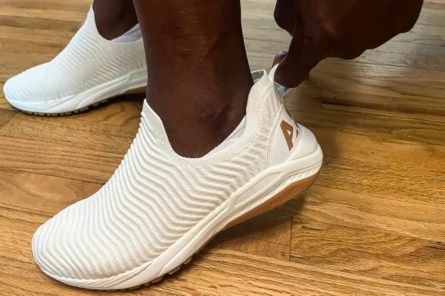 A person uses a heel tag to adjust the APL Men's TechLoom Travelers