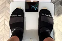 A person stands on the Arboleaf CS10E Segmental Body Scale in socks