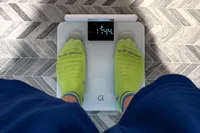 A person stands on the Arboleaf CS10E Segmental Body Scale on a tile floor