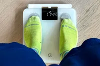 A person stands on the Arboleaf CS10E Segmental Body Scale in socks