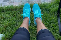 A person sits outside while wearing the Asics Women's Gel-Dedicate 8 Pickleball Shoes