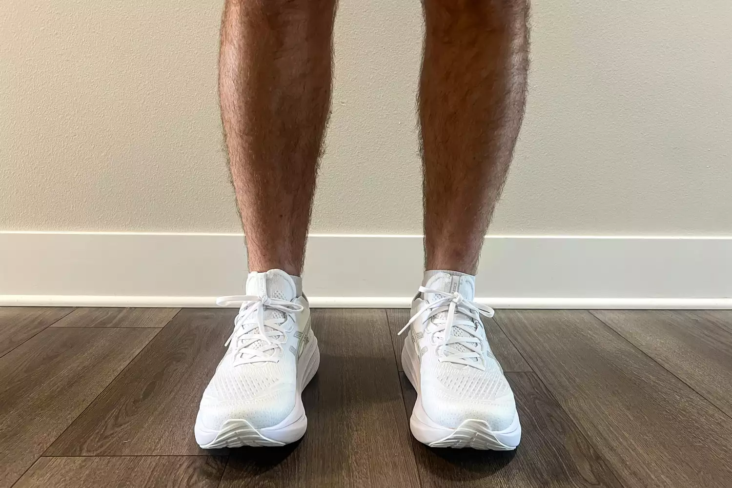 The Asics Men's GEL-NIMBUS 27 worn on a wooden floor