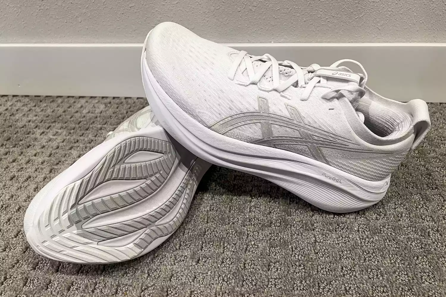 Two Asics Men's GEL-NIMBUS 27 sneakers posed on carpet