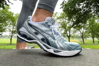 A person stands on a stone step while wearing the Asics Men's Gel-Kayano 14 Sneakers