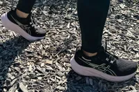 Woman walks on wooden piece by wearing Asics Women's Gel-Nimbus 26