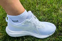 A person wears the Asics Women's Gel-Contend 9 Walking Shoes in grass