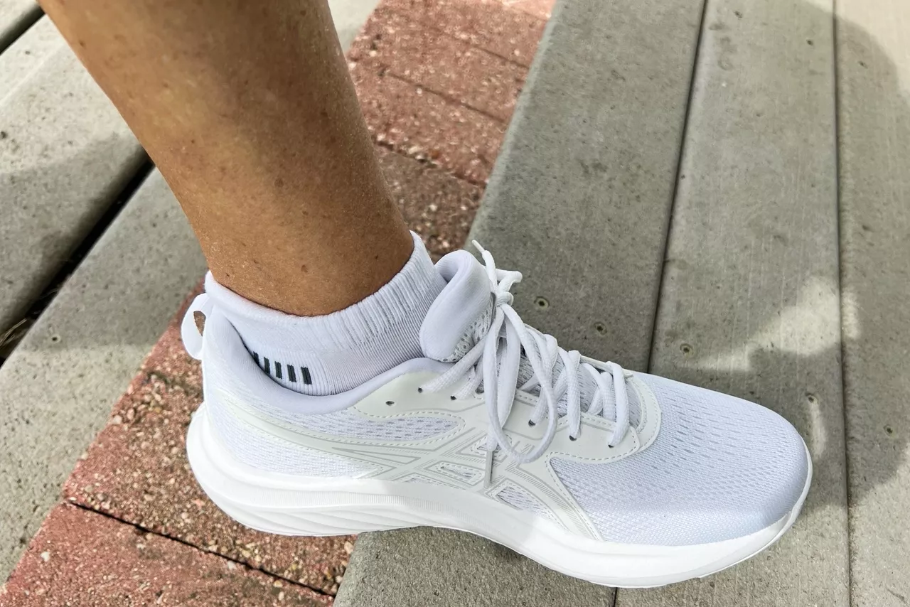 A person rests their foot on a wooden step while wearing the Asics Women's Gel-Contend 9 Walking Shoes