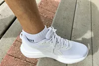 A person rests their foot on a wooden step while wearing the Asics Women's Gel-Contend 9 Walking Shoes