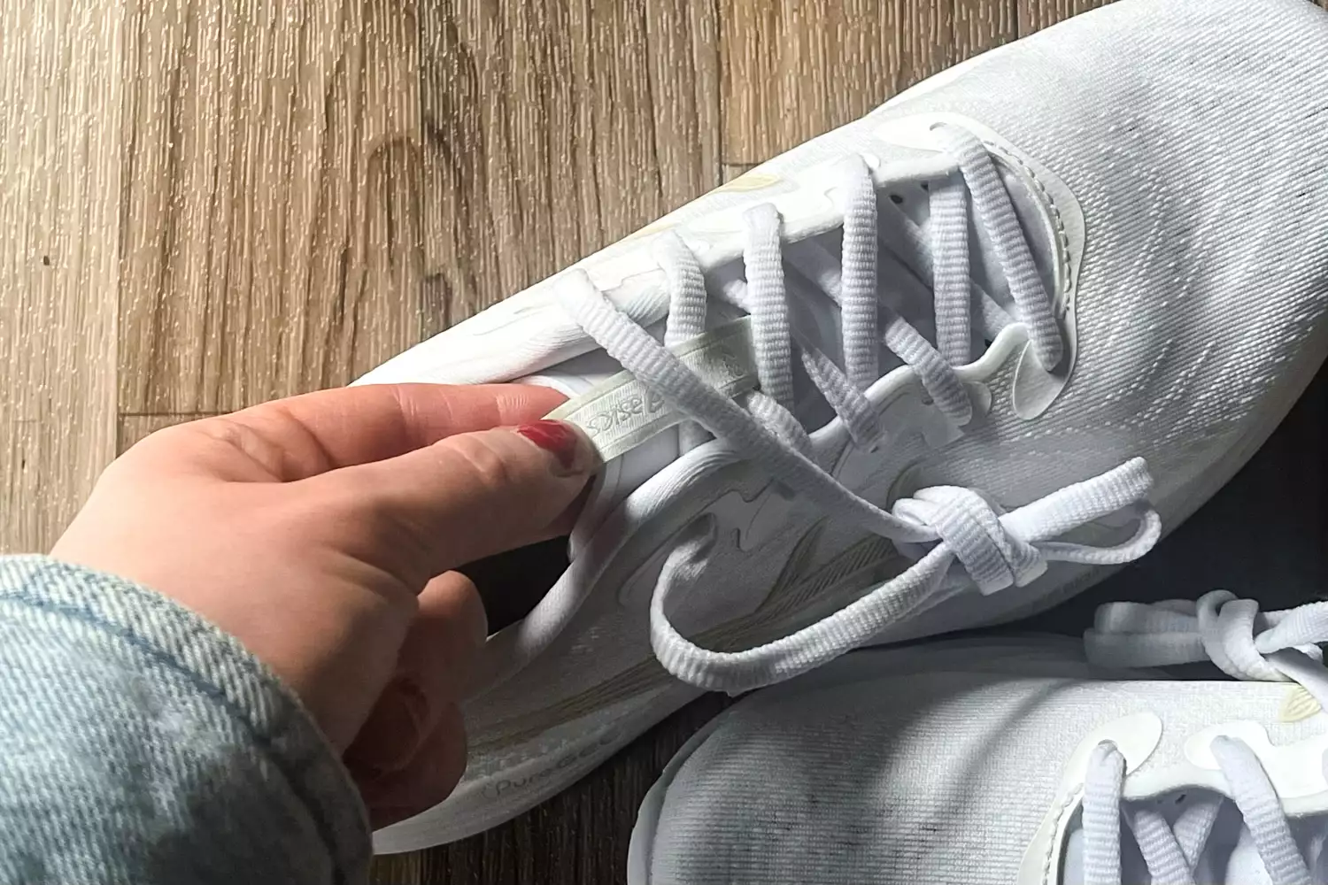 A person touches the tongue of the Asics Women's Gel-Cumulus 27 Running Shoes