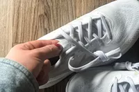 A person touches the tongue of the Asics Women's Gel-Cumulus 27 Running Shoes