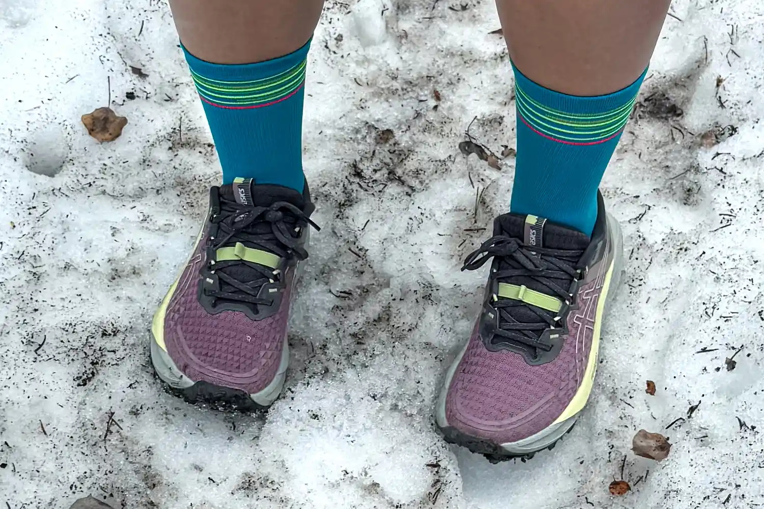 A person wears the Asics Women's Gel-Trabuco 13 Trail Running Sneakers in the snow
