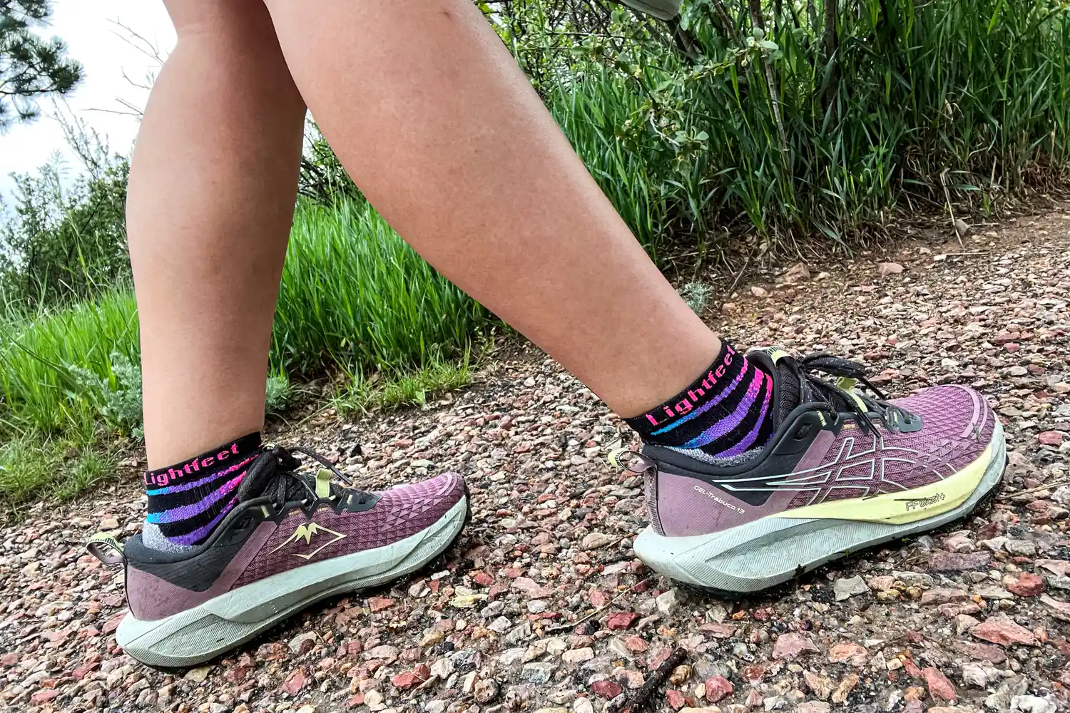 A person walking on a trail wearing Asics Women's Gel-Trabuco 13 Trail Running Sneakers