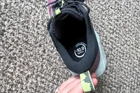A person pulls the tab on the back of the Asics Women's Gel-Trabuco 13 Trail Running Sneaker