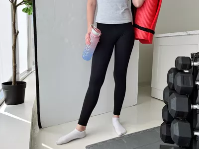 Person wearing Athleta leggings and holding a yoga mat and water bottle
