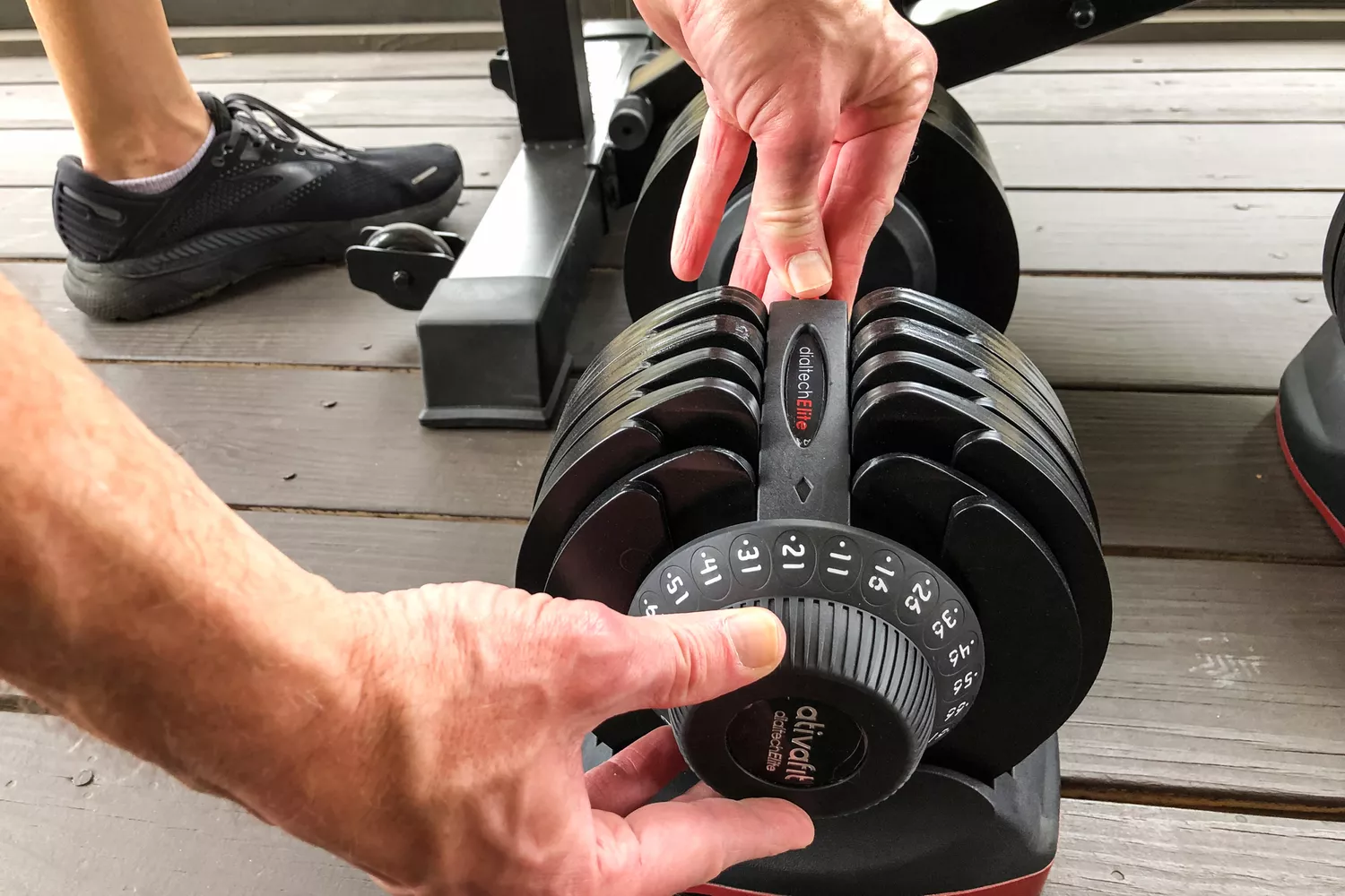 A person changes the weight on the Ativafit Adjustable Dumbbell Set