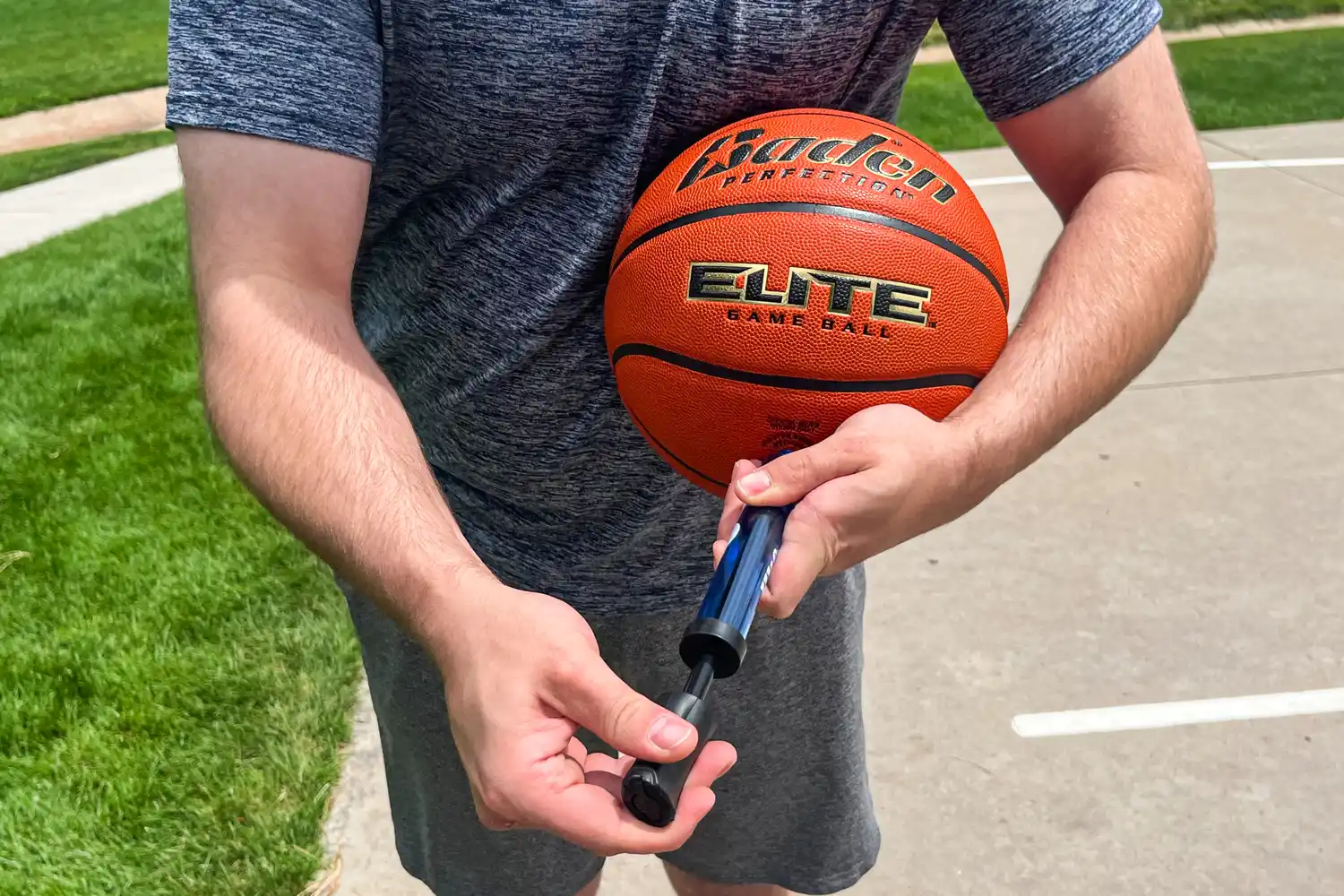 A person fills the Baden Elite Game Basketball with air