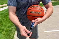 A person fills the Baden Elite Game Basketball with air