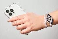 A person wears the Bellabeat Leaf Urban Smart Jewelry Health Tracker on their wrist while holding a cell phone