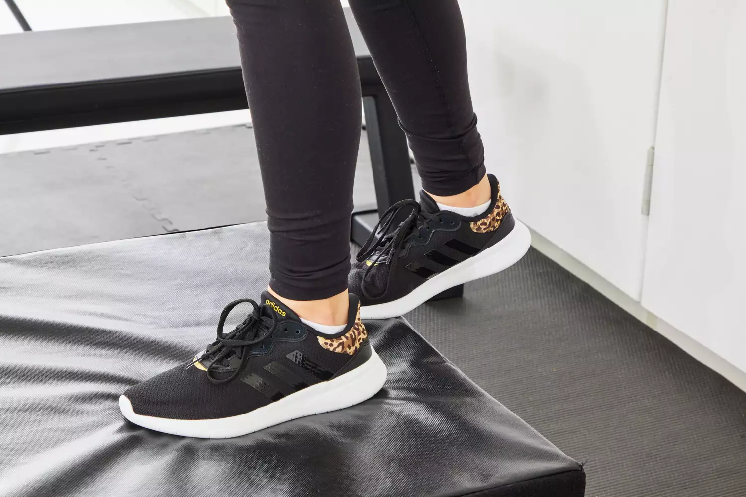 Person wearing Adidas Women's Cloudfoam Qt Racer Running Shoes on a black mat