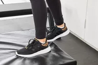 Person wearing Adidas Women's Cloudfoam Qt Racer Running Shoes on a black mat