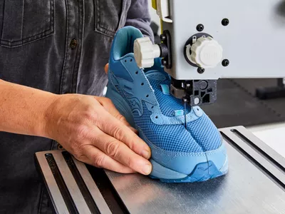 Person cutting a Saucony Men's Cohesion 15 Running Shoe in half