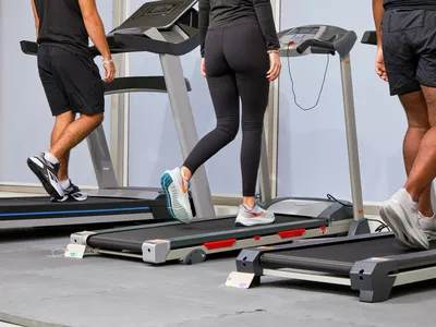 Three people walking on three treadmills wearing different shoes