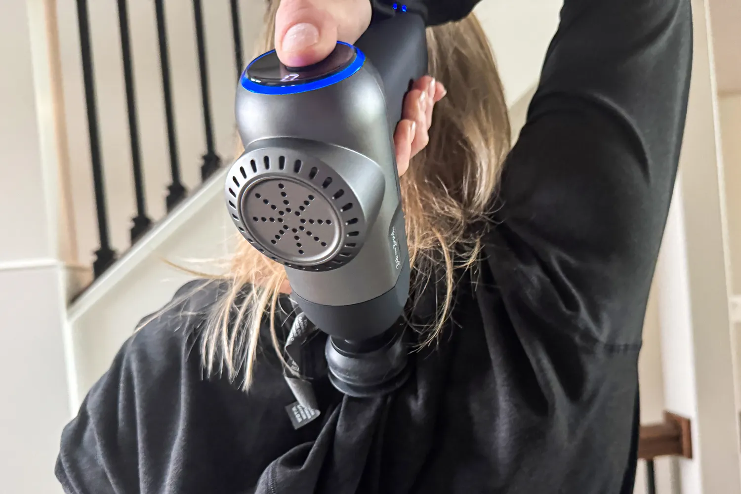 A person uses the Bob and Brad C2 Massage Gun on their back