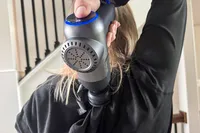 A person uses the Bob and Brad C2 Massage Gun on their back