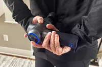 A person uses the Bob and Brad C2 Massage Gun on their back
