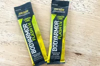 Two packets of BodyArmor Flash IV Lemon Lime electrolyte drink mix displayed on a wooden surface