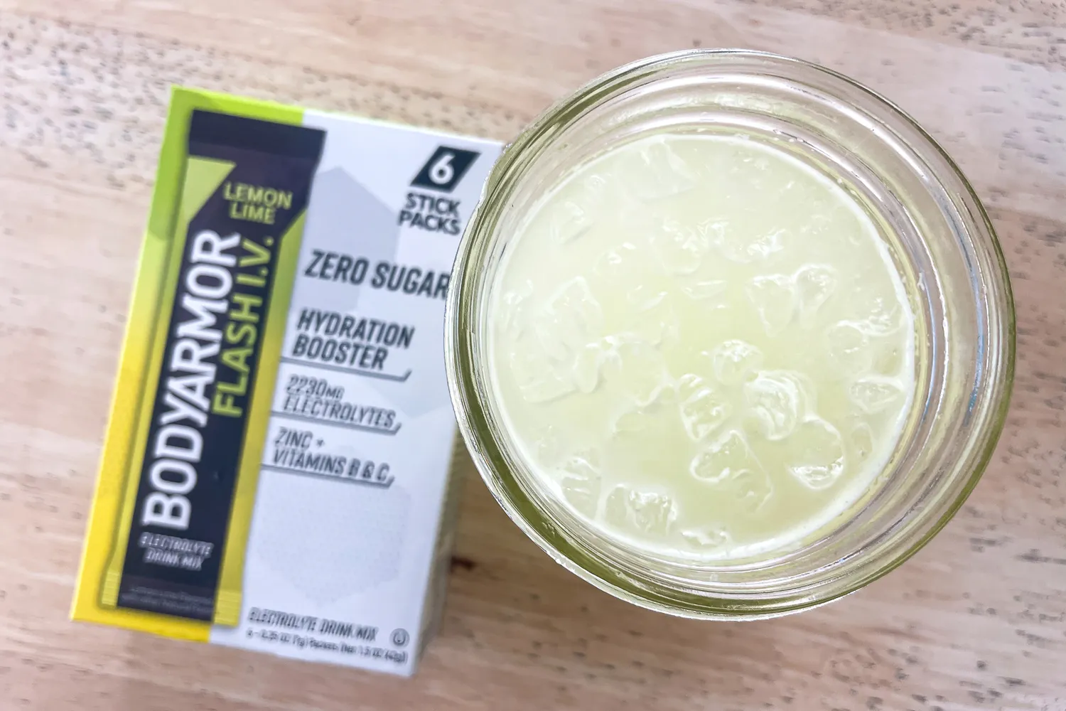 A glass of prepared lemonlime BodyArmor Flash IV drink beside its packaging