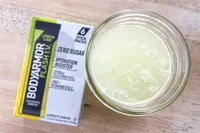 A glass of prepared lemonlime BodyArmor Flash IV drink beside its packaging