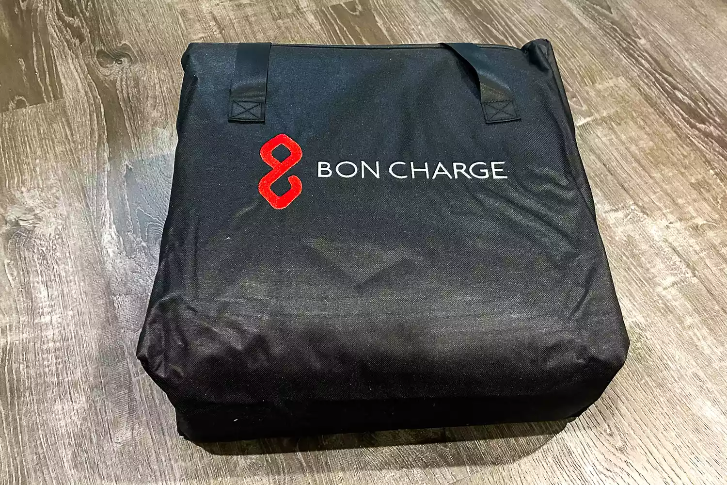 A folded Bon Charge Infrared Sauna Blanket on a wooden floor