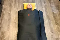 A person laying in the Bon Charge Infrared Sauna Blanket placed in a wooden floor