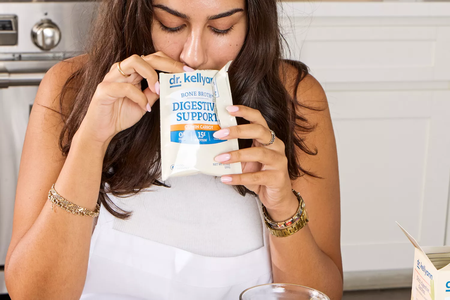 A person smells an open packet of Dr. Kellyann Bone Broth + Digestive Support