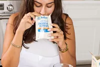 A person smells an open packet of Dr. Kellyann Bone Broth + Digestive Support