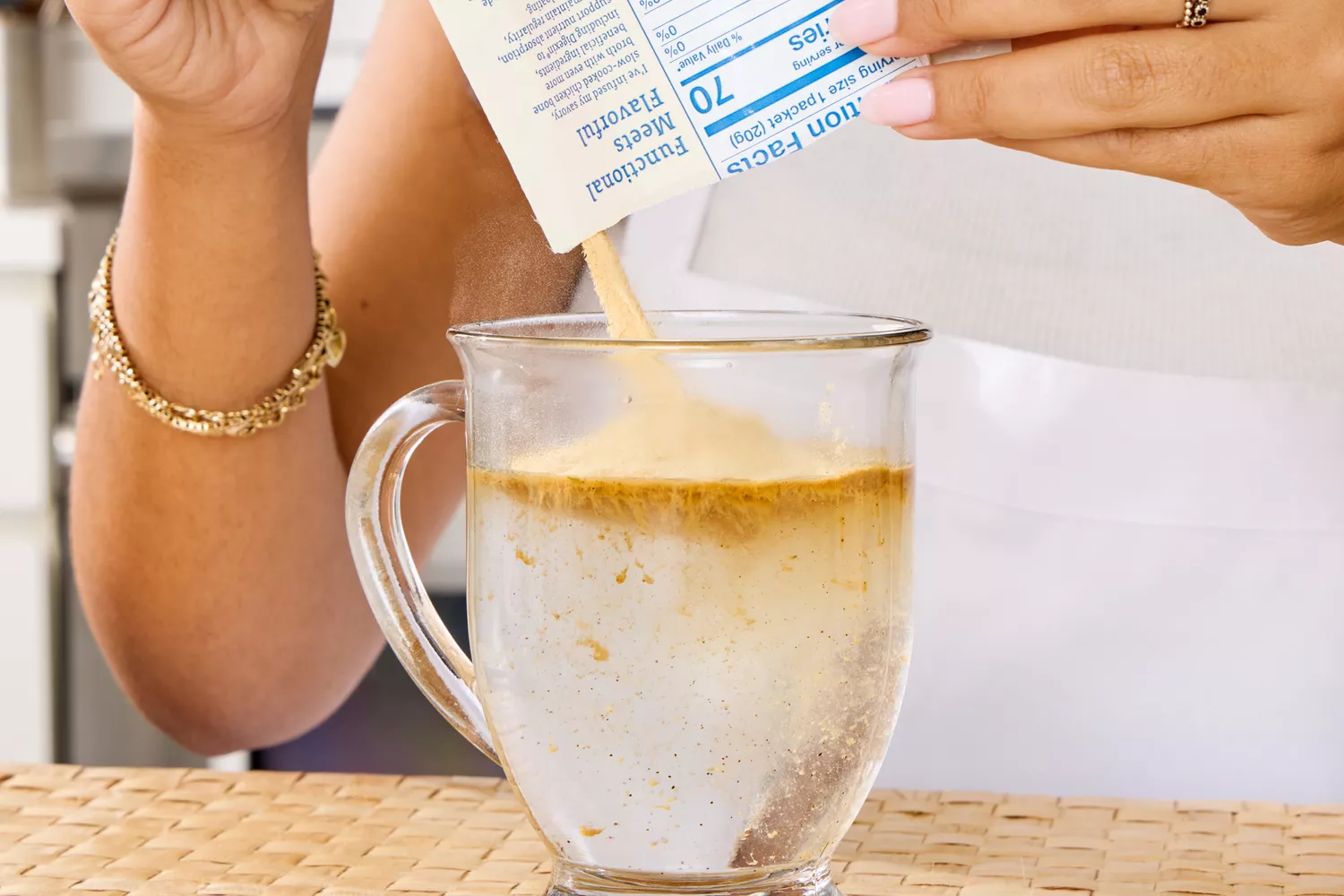 A person pours Dr. Kellyann Bone Broth + Digestive Support into water