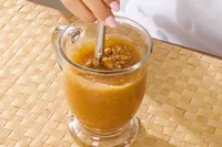 A person stirs the Dr. Kellyann Bone Broth + Digestive Support in a glass
