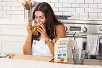 A person drinks a glass of Dr. Kellyann Bone Broth + Digestive Support