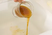 A person pours Dr. Kellyann Bone Broth + Digestive Support into a sink
