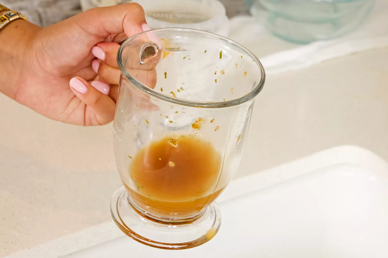 A person holds up a glass of Dr. Kellyann Bone Broth + Digestive Support