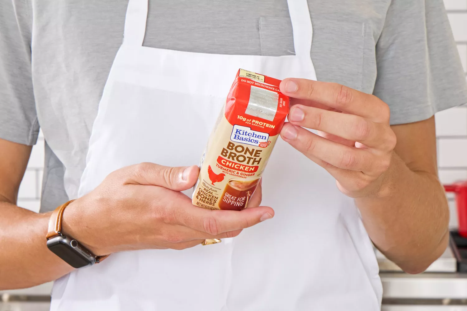 A person reads the back of the Kitchen Basics Turmeric & Ginger With Lemongrass Chicken Bone Broth