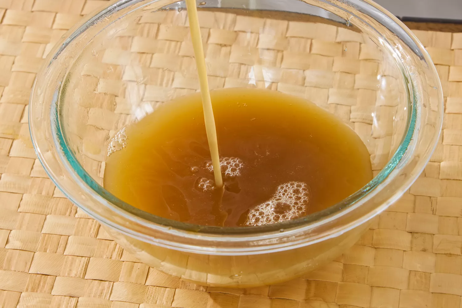 Kitchen Basics Turmeric & Ginger With Lemongrass Chicken Bone Broth is poured into a glass bowl