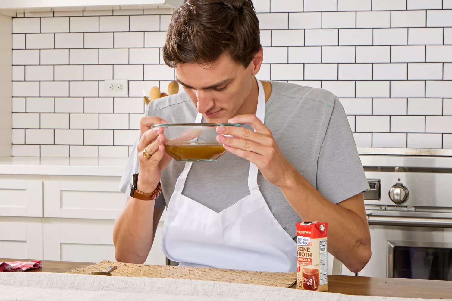 A person smells a bowl of Kitchen Basics Turmeric & Ginger With Lemongrass Chicken Bone Broth