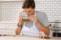 A person smells a bowl of Kitchen Basics Turmeric & Ginger With Lemongrass Chicken Bone Broth