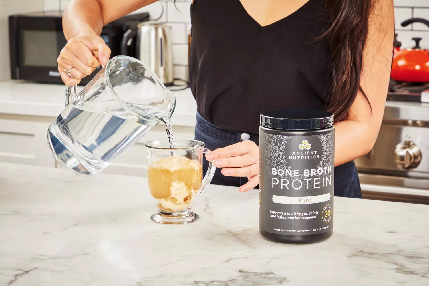 A person pours water into Ancient Nutrition Bone Broth Protein powder