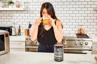 A person drinks a glass of Ancient Nutrition Bone Broth Protein