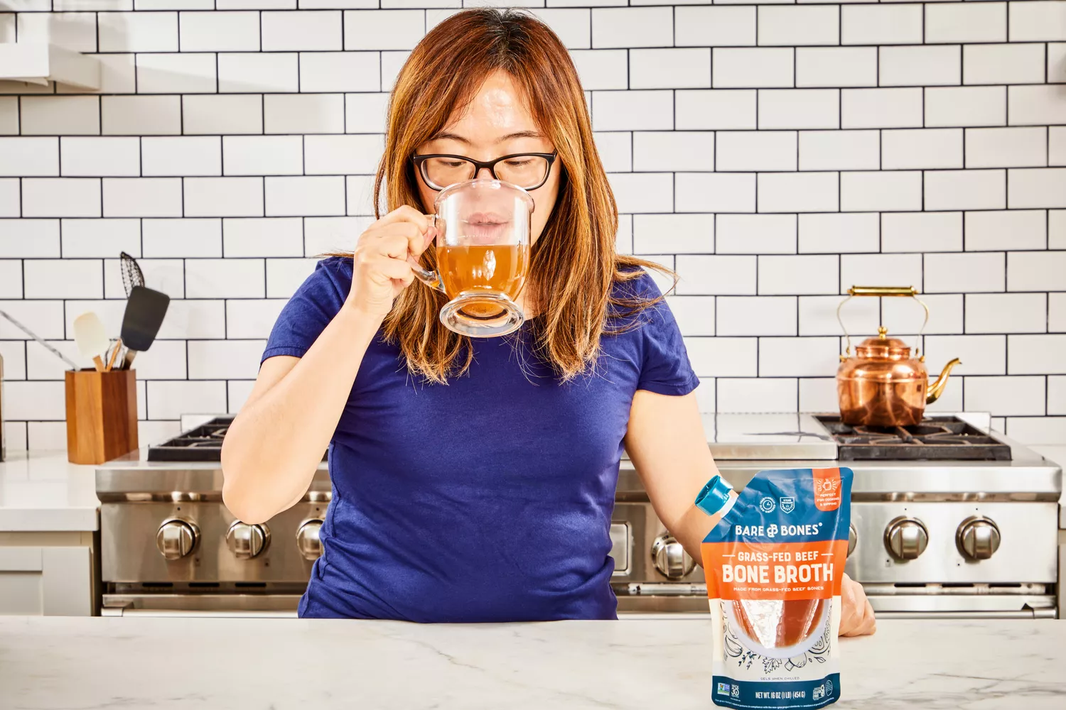 A person drink a glass of Bare Bones Grass-Fed Beef Organic Bone Broth